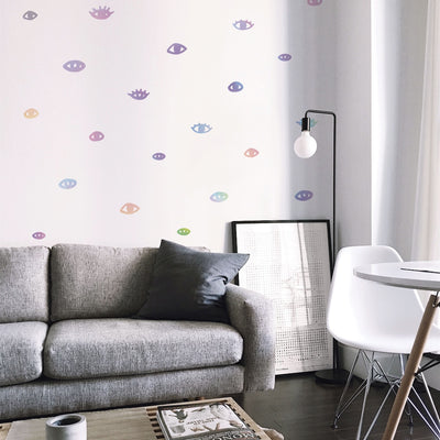 Holographic You Are Seen wall decals on a white living room wall with a grey sofa, seating area, and coffee table — available from Tempaper.