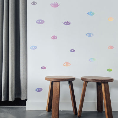 Holographic You Are Seen wall decals from Tempaper one a wall with two brown stools.