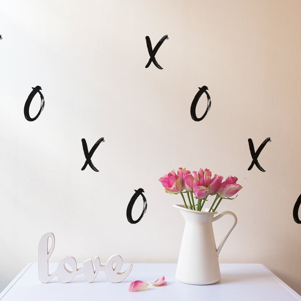 Black XOXO wall decals from Tempaper on a wall behind a table with a white vase and the word "love" in cursive.