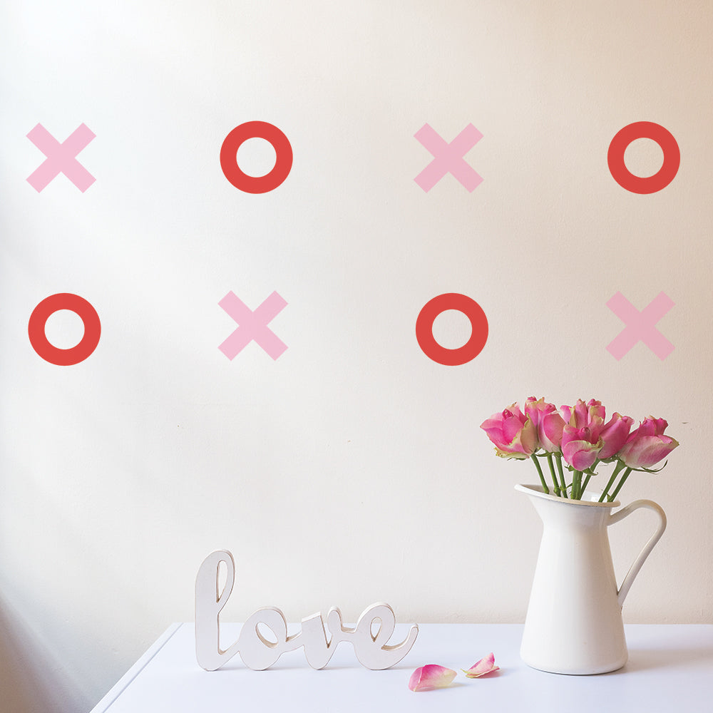Tempaper's Tic Tac Toe wall decals on a wall behind a white sign that says "love" and a white pitcher holding pink roses.