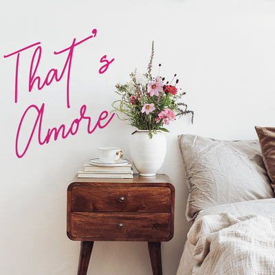 That's Amore wall decals from Tempaper decorating the wall behind a wood nightstand holding a stack of books, coffee mug, and flowers.