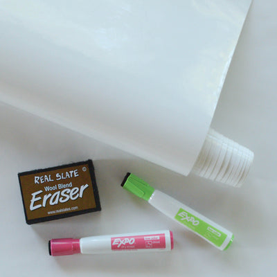 A roll of dry erase wallpaper from Tempaper resting next to an eraser and two Expo markers.