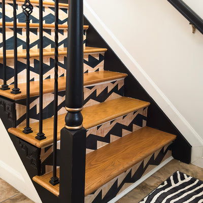 A geometric wallpaper in natural and wood color covering the front of stair risers. #color_tiger-stripe