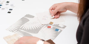 Image of girl using pantone swatches to match to a grey Feather Flock wallpaper sample.