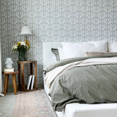 A geometric peel and stick wallpaper print on the wall behind a modern styled bed with a wooden side table. #color_urban-grey