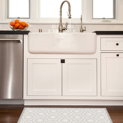 Tempaper's Hello Sunshine Vinyl rug shown in grey in front of a white sink in a kitchen.
