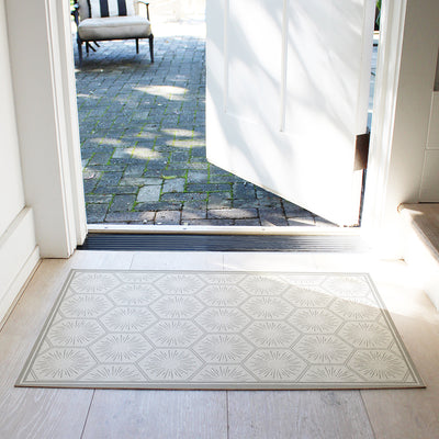 Tempaper's Hello Sunshine Vinyl rug shown in grey in front of a white door.