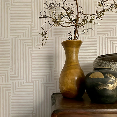 Close up of geometric peel and stick wallpaper next to a wood vase and table