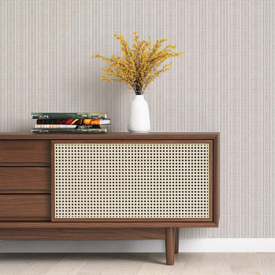 Batik Stripe Removable Wallpaper - A wood sideboard with books and a white vase on top in a room featuring Batik Stripe Peel And Stick Wallpaper in french grey | Tempaper#color_french-grey