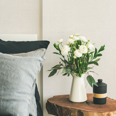 Burlap Removable Wallpaper - A bed and wood nightstand with a plant on top in a bedroom featuring Burlap Peel And Stick Wallpaper in linen burlap | Tempaper#color_linen-burlap