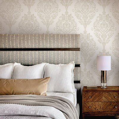 Estate Damask Non-Pasted Wallpaper - A bedroom and nightstand in front of Estate Damask Unpasted Wallpaper in champagne damask | Tempaper#color_champagne-damask