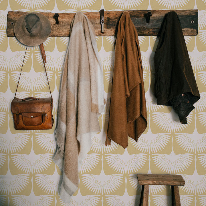 Feather Flock Removable Wallpaper - A wood coat hanger with scarves on a wall featuring Tempaper's Feather Flock Peel And Stick Wallpaper in golden hour scallops#color_golden-hour-scallops