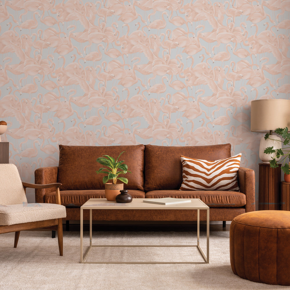 Fun pastel flamingo wallpaper behind a dark colored couch #color_pastel-pink-and-blue