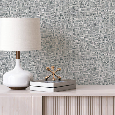 Glyph Geo Non-Pasted Wallpaper - A wood dresser with a white lamp and books in front of Glyph Geo Unpasted Wallpaper in graphite geo | Tempaper#color_graphite-geo