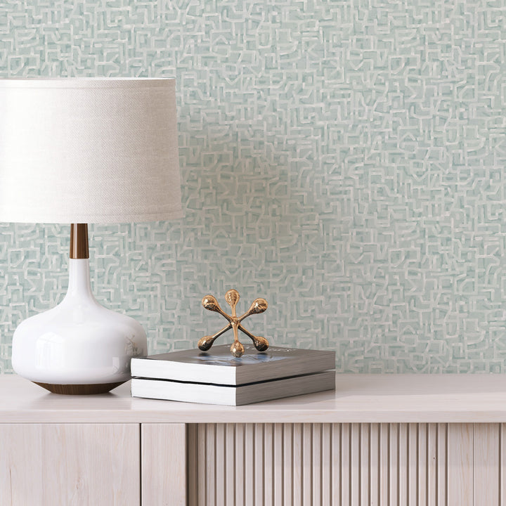 Glyph Geo Non-Pasted Wallpaper - A wood dresser with a white lamp and books in front of Glyph Geo Unpasted Wallpaper in mint geo | Tempaper#color_mint-geo