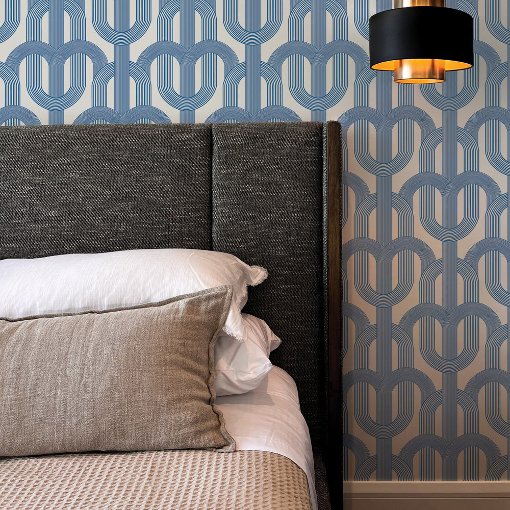 Blue Lattice wallpaper print is on a wall behind a dark grey upholstered bed #color_ice-blue