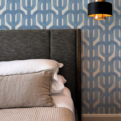 Blue Lattice wallpaper print is on a wall behind a dark grey upholstered bed #color_ice-blue