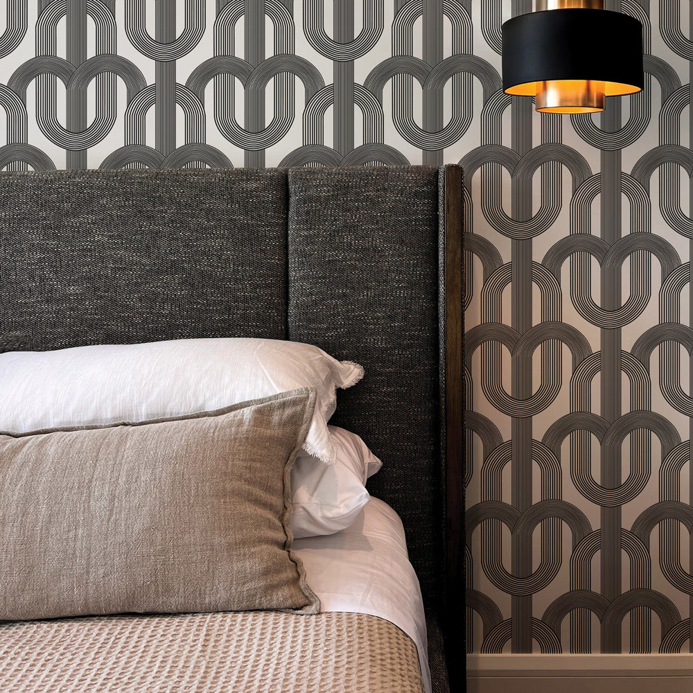Dark grey  wallpaper print of overlapping arches is on a wall behind a dark grey upholstered bed  #color_ink