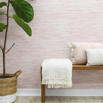 Moire Dots Removable Wallpaper - A wood bench with pillows and a white blanket in front of a wall featuring Tempaper's Moire Dots Peel And Stick Wallpaper in coral dots | Tempaper#color_coral-dots