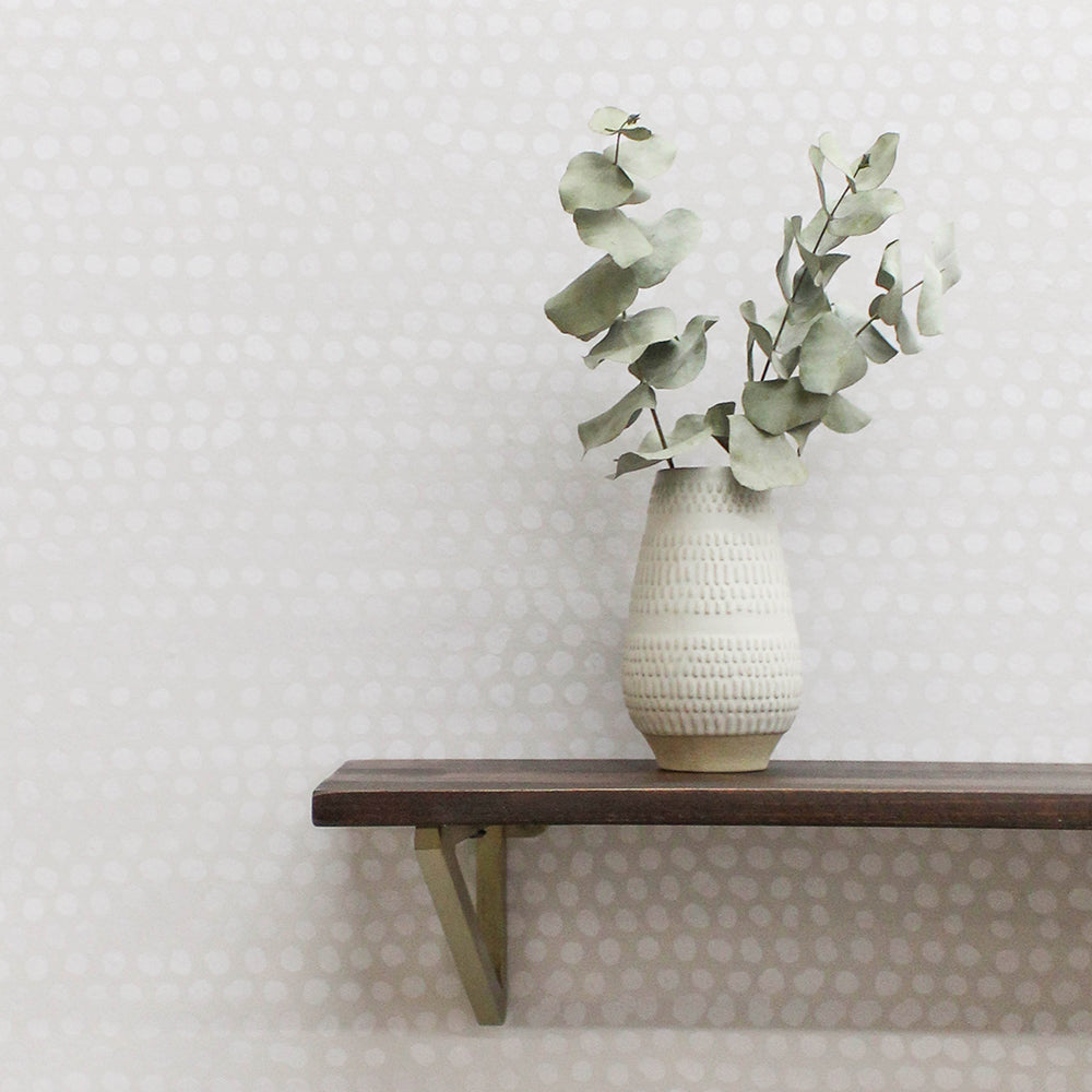 Moire Dots Removable Wallpaper - A wood shelf with a white vase and plant on a  wall featuring Tempaper's Moire Dots Peel And Stick Wallpaper in pearl grey dots | Tempaper#color_pearl-grey-dots