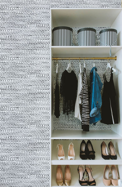 Moire Dots Removable Wallpaper - A closet with shoes and apparel featuring Tempaper's Moire Dots Peel And Stick Wallpaper in black and white dots | Tempaper#color_black-and-white-dots