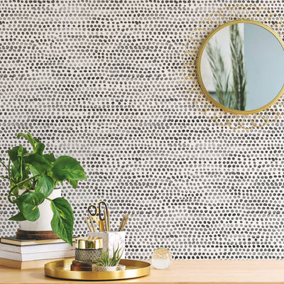 Moire Dots Removable Wallpaper - Three books, a plant, and gold mirror  in front of a wall featuring Tempaper's Moire Dots Peel And Stick Wallpaper in black and white dots | Tempaper#color_black-and-white-dots