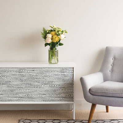 Moire Dots Removable Wallpaper - A white sideboard with a plant on top featuring Tempaper's Moire Dots Peel And Stick Wallpaper in black and white dots | Tempaper#color_black-and-white-dots
