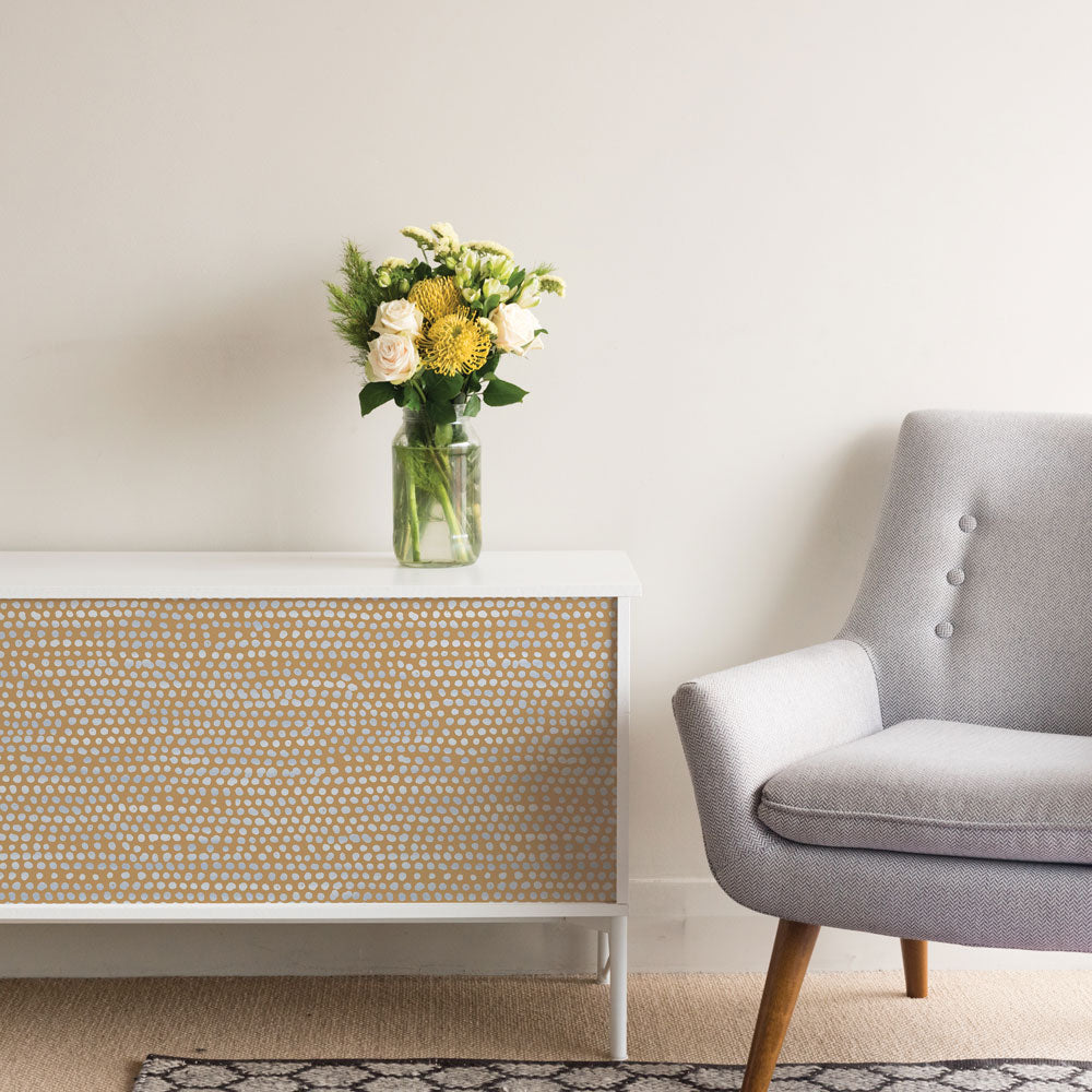 Moire Dots Removable Wallpaper - A white sideboard with a plant on top featuring Tempaper's Moire Dots Peel And Stick Wallpaper in toasted turmeric dots | Tempaper#color_toasted-turmeric-dots
