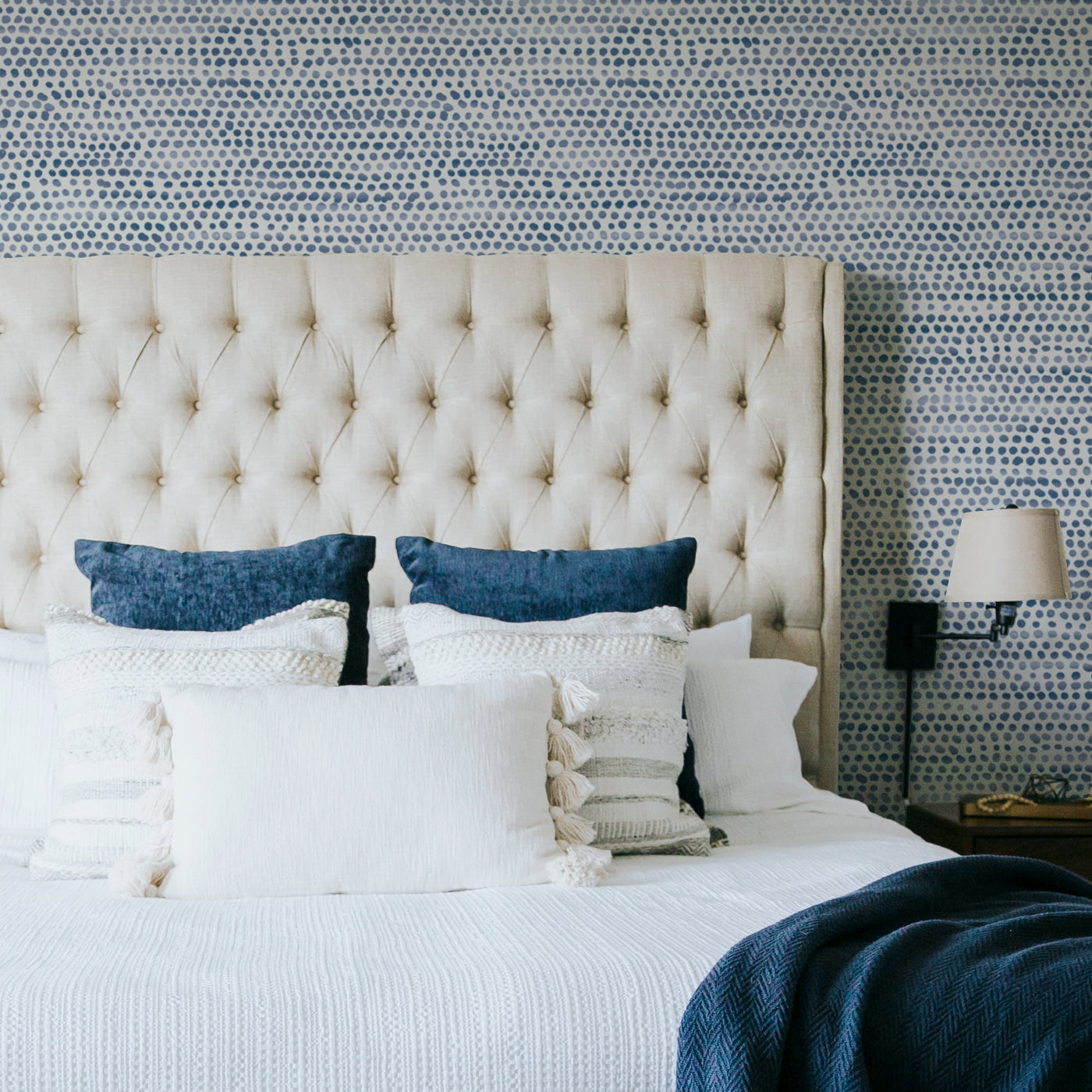 Moire Dots Removable Wallpaper - A bed with a tan headboard in front of a wall featuring Tempaper's Moire Dots Peel And Stick Wallpaper in blue moon dots | Tempaper#color_blue-moon-dots