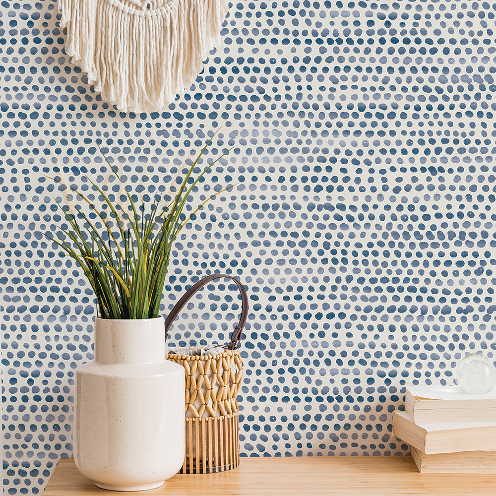 Moire Dots Removable Wallpaper - Three books and a white vase on a shelf in front of a wall featuring Tempaper's Moire Dots Peel And Stick Wallpaper in blue moon dots | Tempaper#color_blue-moon-dots