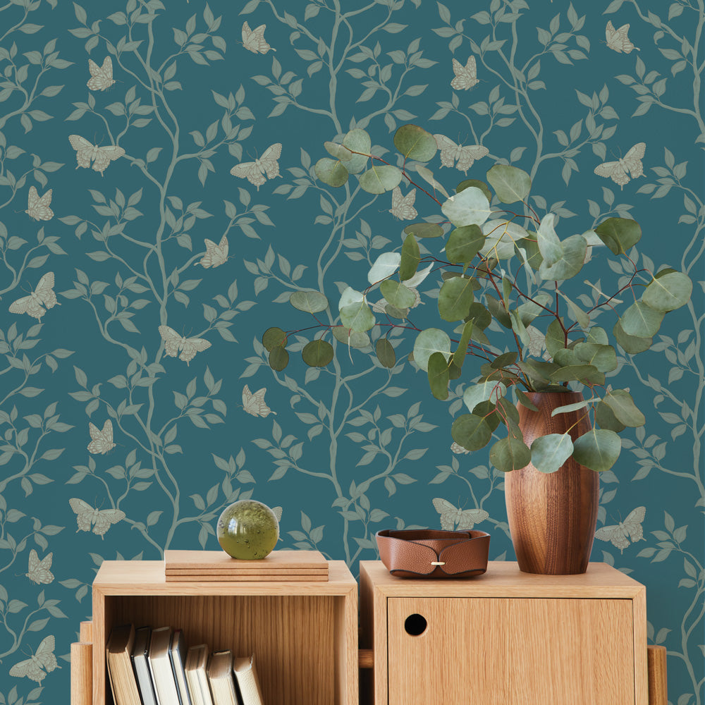 Monarch Non-Pasted Wallpaper - A wood dresser with a plant in a room featuring Monarch Unpasted Wallpaper in spruce | Tempaper#color_spruce