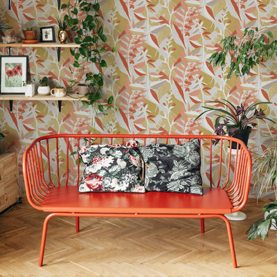 A pink and orange garden wallpaper behind a metal bench surrounded by plants #color_pink-punch-petite