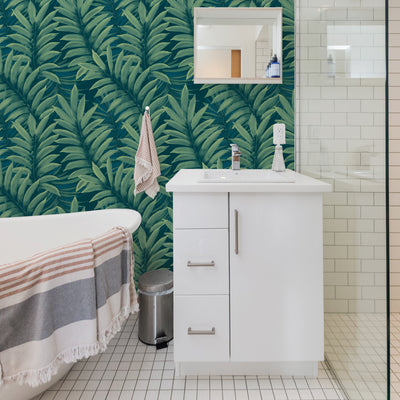 A bathroom with a white vanity and Tempaper's Palm Leaves Peel And Stick Wall Murals.