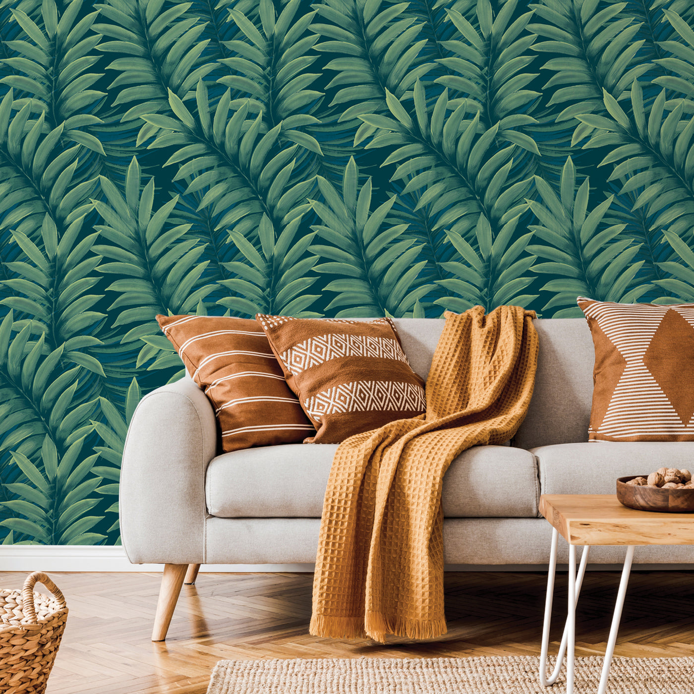 Tempaper's Palm Leaves Temporary Wall Murals behind a grey couch with brown pillows.