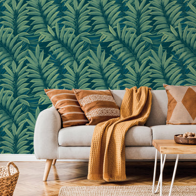 Tempaper's Palm Leaves Temporary Wall Murals behind a grey couch with brown pillows.