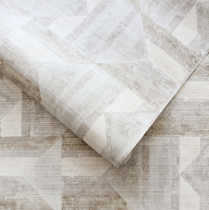 A slightly unraveled roll of Quilted Patchwork peel and stick wallpaper.