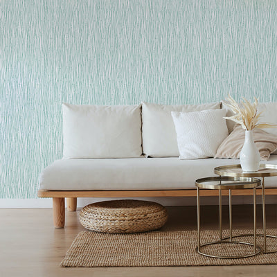 Tempaper's String of Pearls Peel And Stick Wallpaper in green behind a grey couch and bronze coffee table.