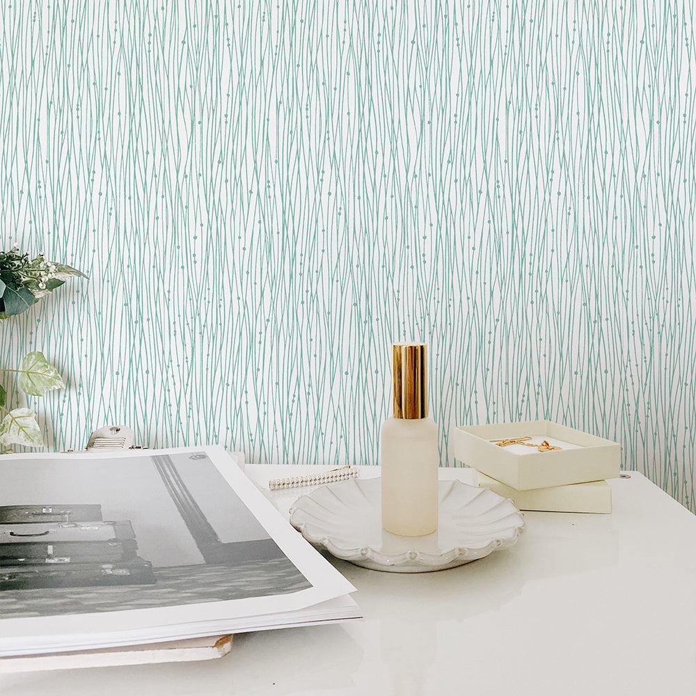 Tempaper's String of Pearls Peel And Stick Wallpaper in green behind a white table.