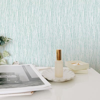 Tempaper's String of Pearls Peel And Stick Wallpaper in green behind a white table.