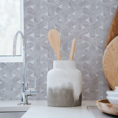 Grey trellis peel and stick wallpaper print applied as a kitchen backsplash behind a sink #color_steel-grey