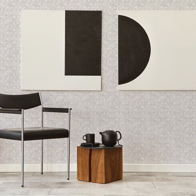 Modern artwork hangs over trellis wallpaper design next to a black chair #color_steel-grey