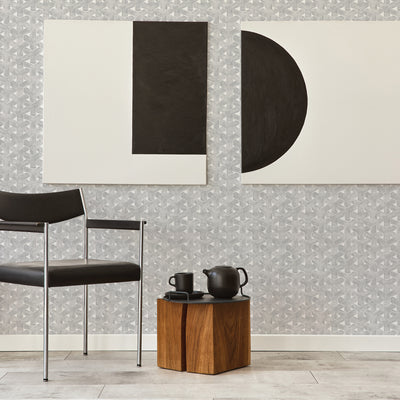 Modern artwork hangs over a grey trellis wallpaper design next to a black chair #color_charcoal