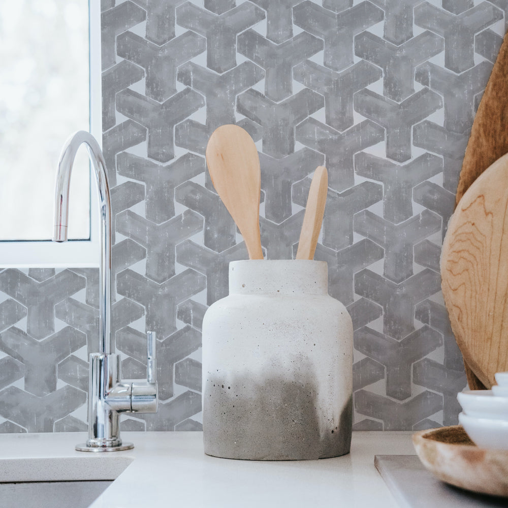 Charcoal grey trellis peel and stick wallpaper print applied as a kitchen backsplash behind a sink  #color_charcoal