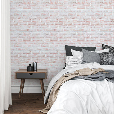 Tempaper's Whitewashed Brick Peel And Stick Wallpaper in a bedroom behind a bed and nightstand.