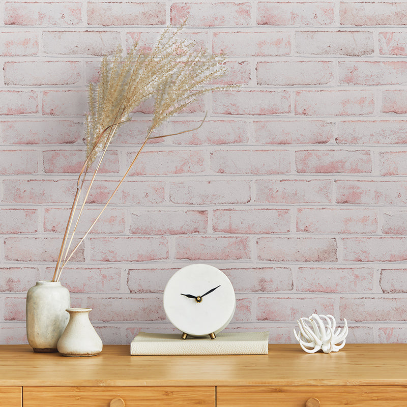 Tempaper's Whitewashed Brick Peel And Stick Wallpaper above a wood dresser with a clock and plant on top.