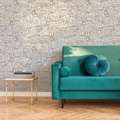 Amalfi WALLPAPER in metallic gold behind a green sofa in a living room.