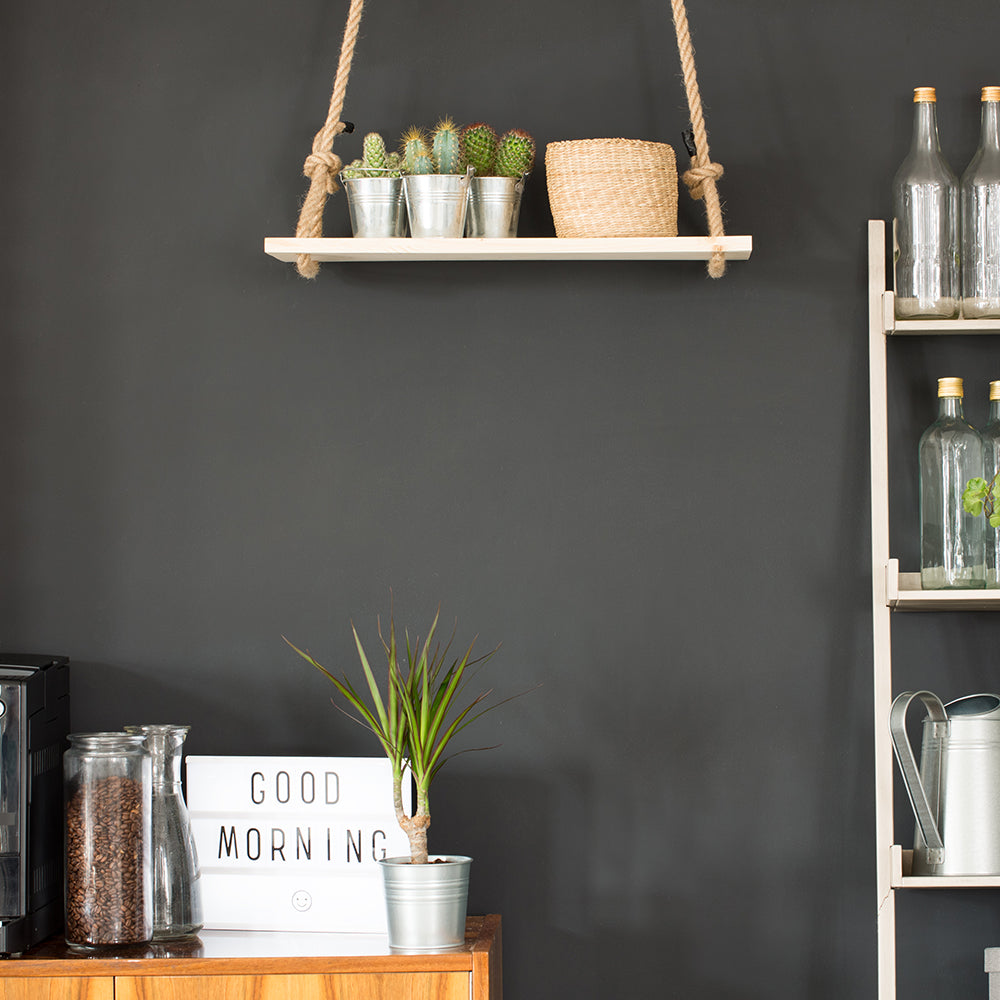 A small kitchen nook with a coffee maker, a "good morning" sign, and a hanging shelf with a wall covered in Tempaper's chalkboard wallpaper.