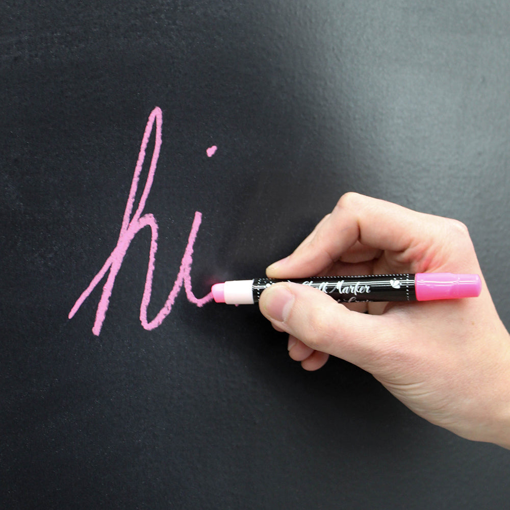 A person writing with a pink Erasable Chalk Marker on a blackboard.