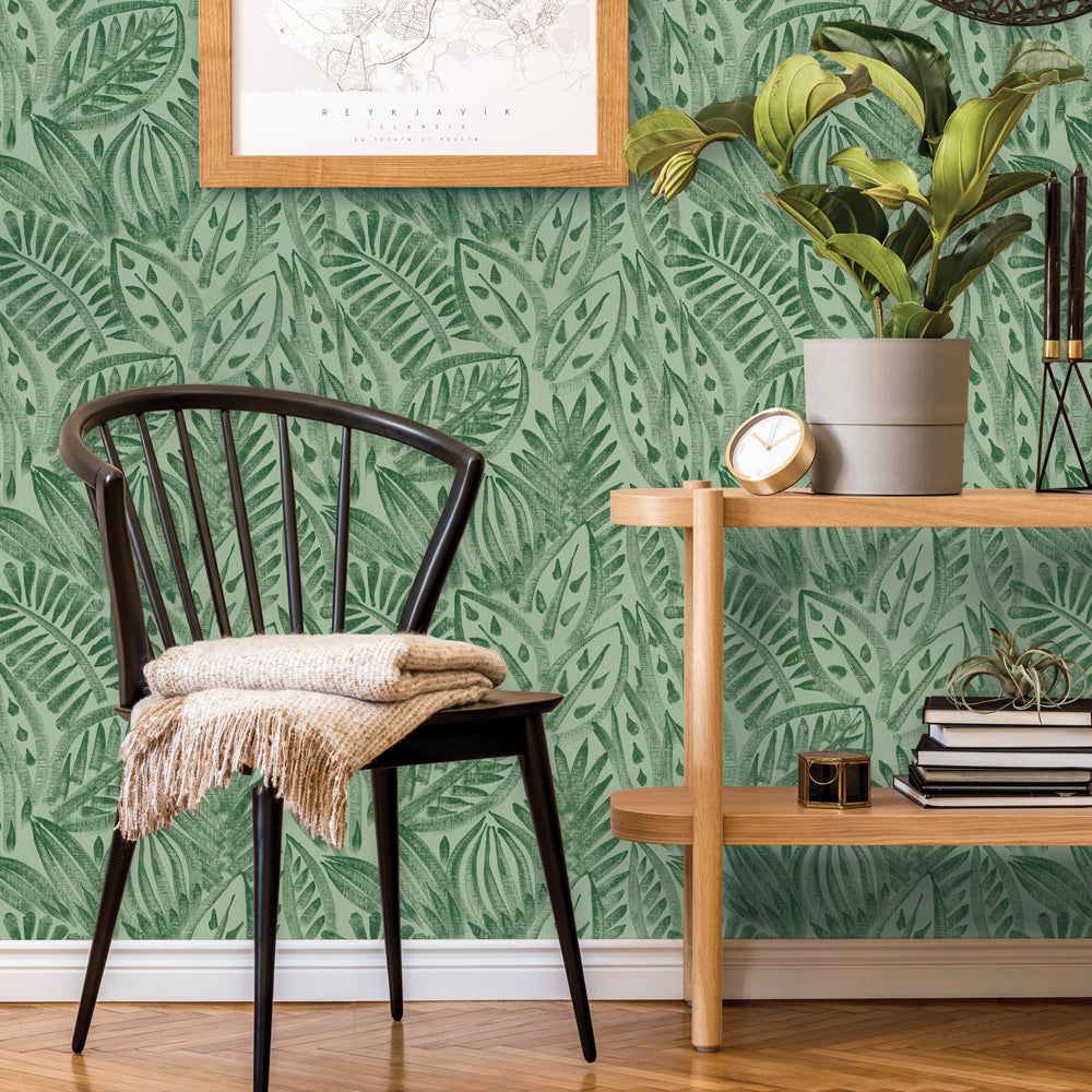 Tempaper's green grove Canvas Palm peel and stick wallpaper shown behind a chair.