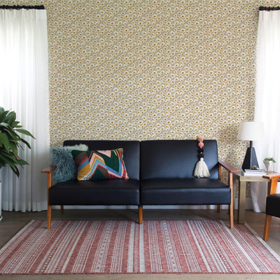 Tempaper's Daisies Peel And Stick Wallpaper By Novogratz shown behind a couch.
